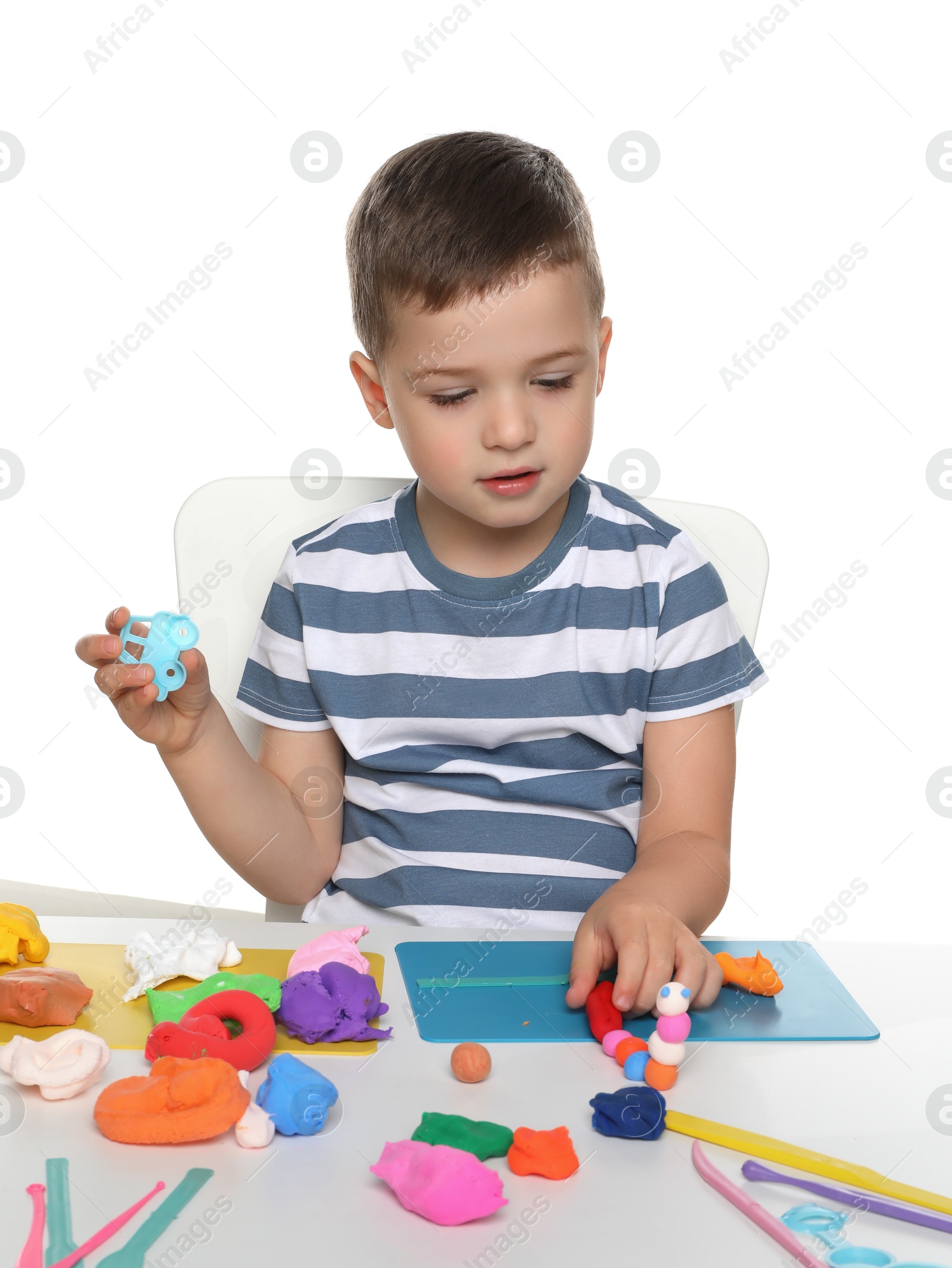 Photo of Little boy sculpting with play dough at table on white background