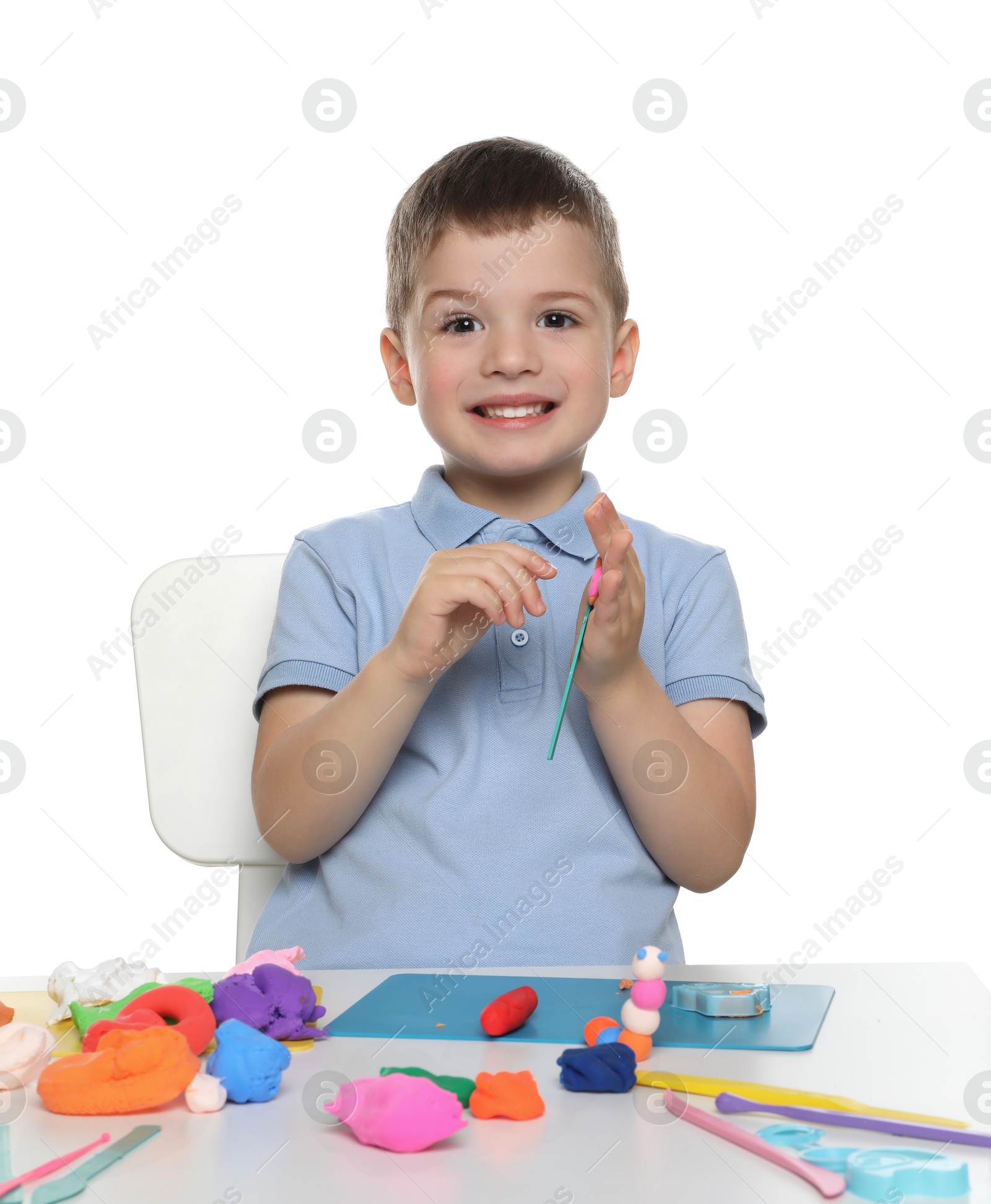 Photo of Smiling boy with play dough handiwork at table on white background