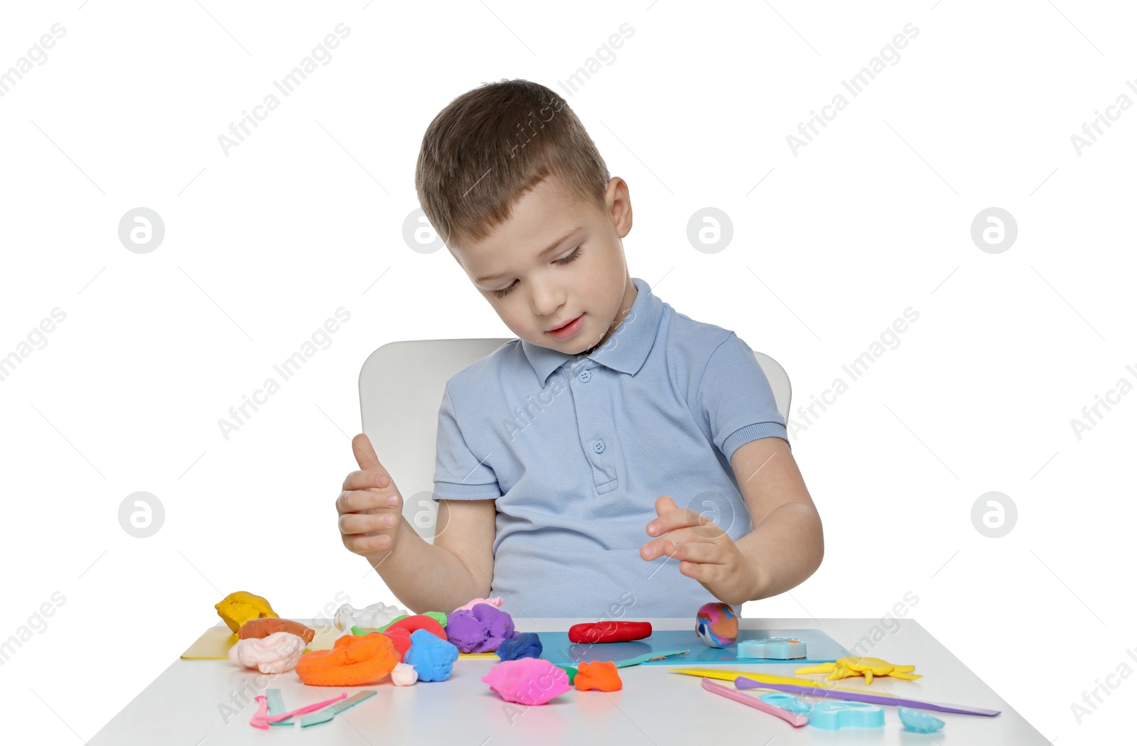 Photo of Little boy sculpting with play dough at table on white background