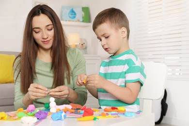 Photo of Son and mother sculpting with play dough at table indoors