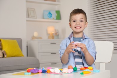 Photo of Smiling boy sculpting with play dough at table in kindergarten. Space for text