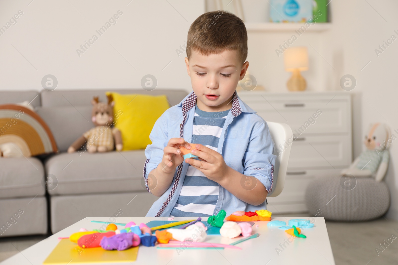 Photo of Little boy sculpting with play dough at table in kindergarten