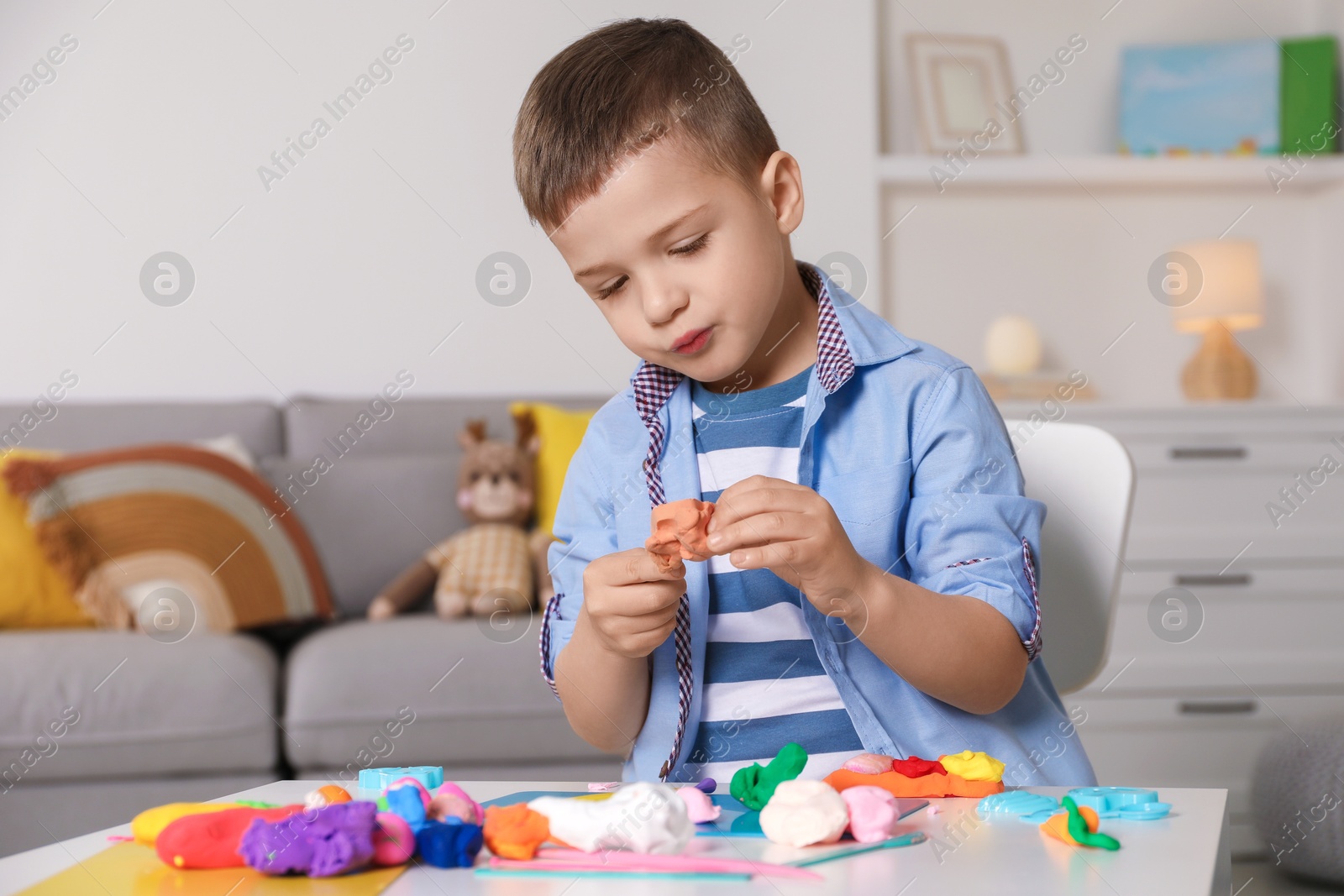 Photo of Little boy sculpting with play dough at table in kindergarten