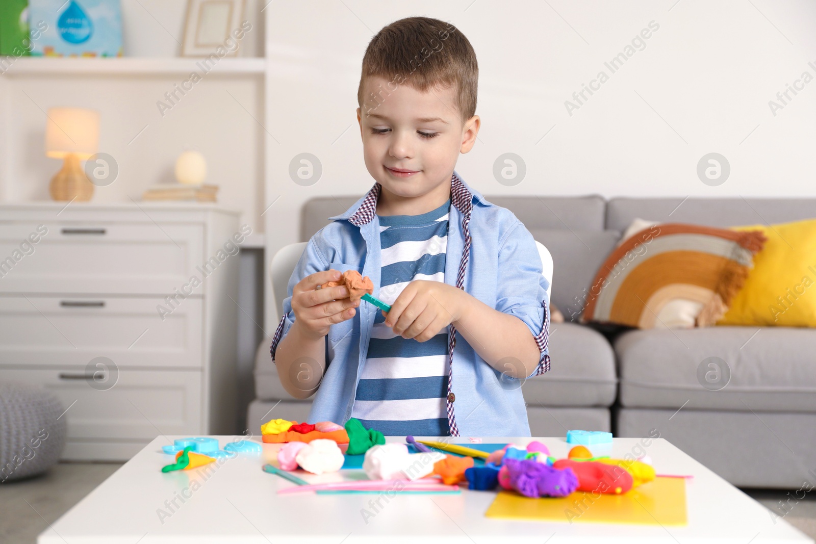 Photo of Little boy sculpting with play dough at table in kindergarten
