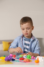 Little boy sculpting with play dough at table in kindergarten