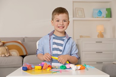 Photo of Portrait of smiling boy at table with play dough in kindergarten