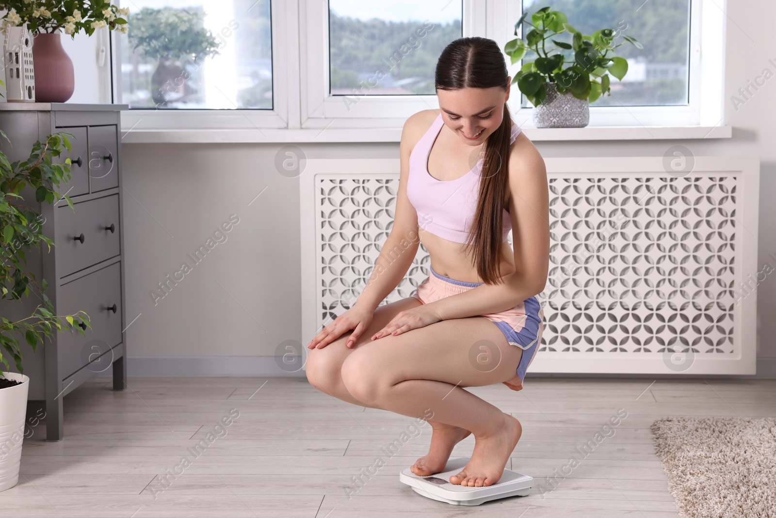 Photo of Happy woman on floor scale at home