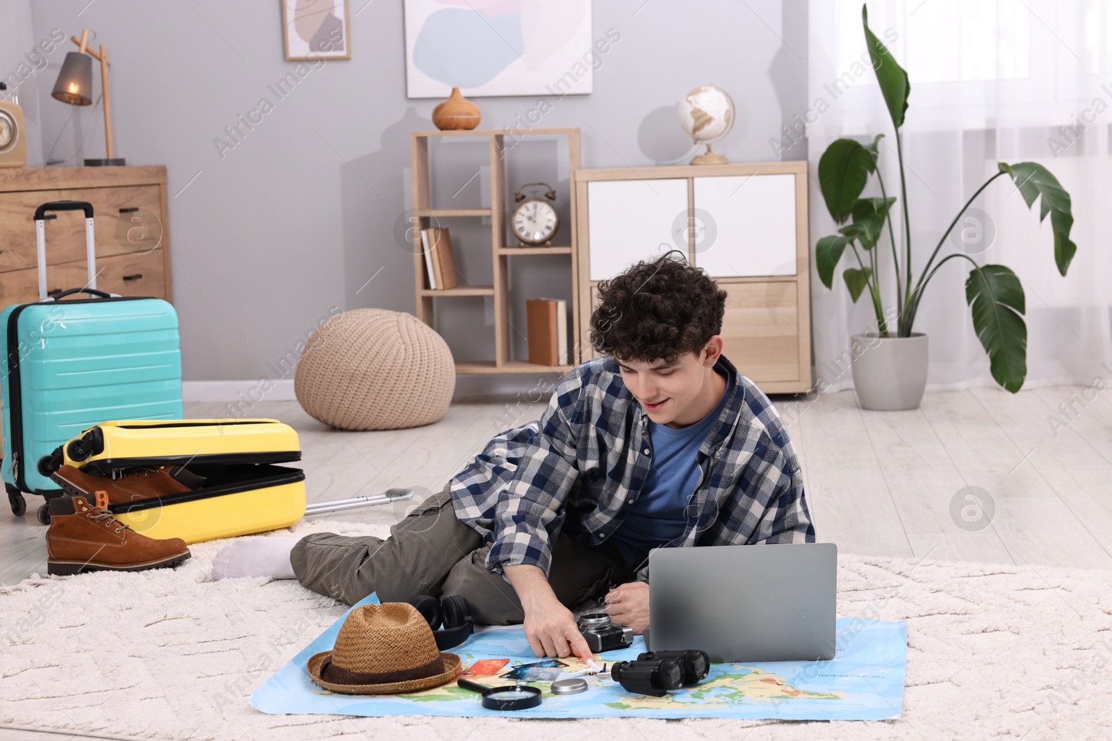 Photo of Travel blogger with laptop and map planning trip at home