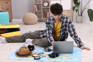 Photo of Travel blogger with laptop and map planning trip at home