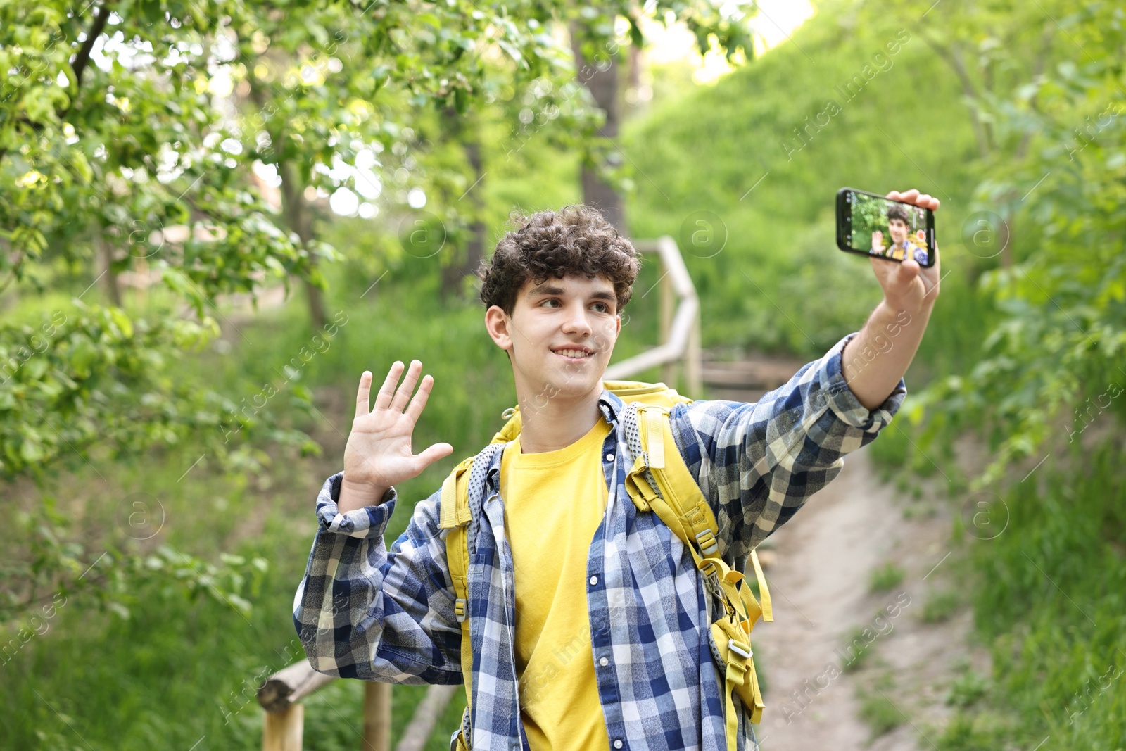 Photo of Smiling travel blogger with smartphone streaming outdoors