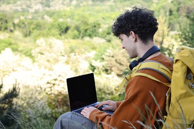 Photo of Travel blogger with backpack using laptop outdoors