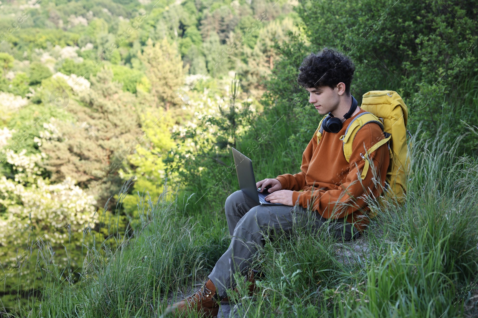 Photo of Travel blogger with backpack using laptop outdoors