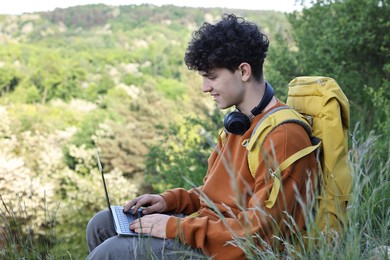 Photo of Travel blogger with backpack using laptop outdoors
