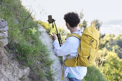 Photo of Travel blogger with smartphone and tripod recording video outdoors