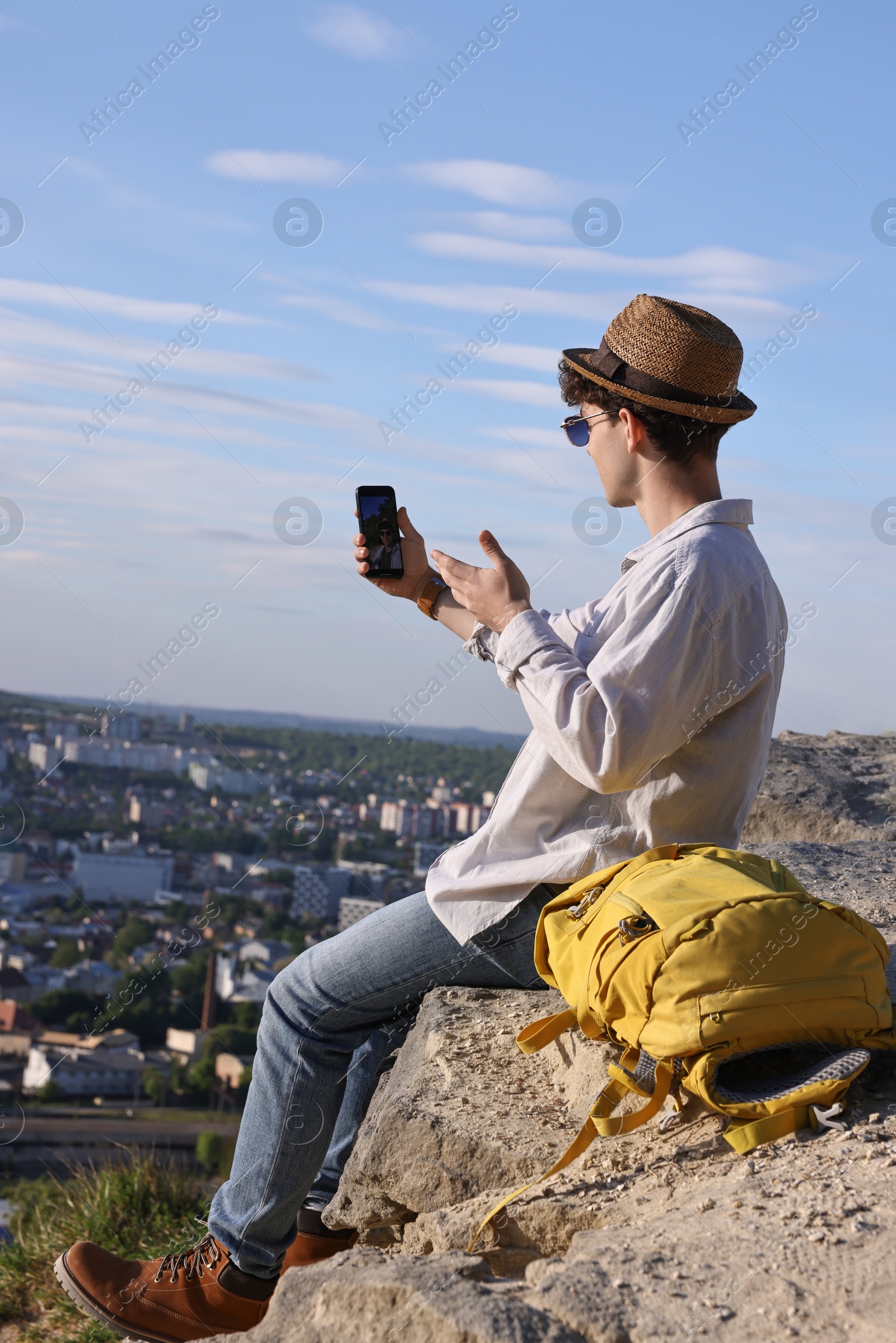 Photo of Travel blogger in straw hat with smartphone streaming outdoors