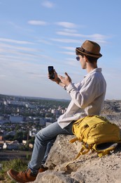 Photo of Travel blogger in straw hat with smartphone streaming outdoors