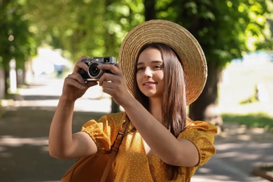 Travel blogger takIng picture with vintage camera outdoors