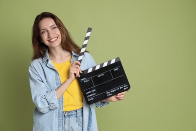Making movie. Smiling woman with clapperboard on green background. Space for text
