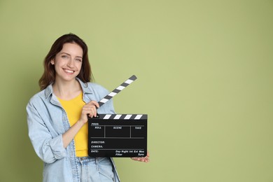 Photo of Making movie. Smiling woman with clapperboard on green background. Space for text