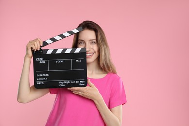 Making movie. Smiling woman with clapperboard on pink background. Space for text