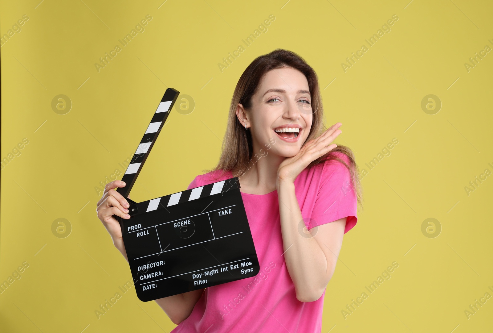 Photo of Making movie. Smiling woman with clapperboard on yellow background