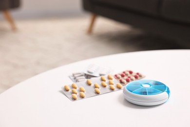 Photo of Different pills and organizer at white table, closeup. Space for text