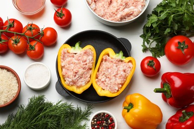 Raw stuffed peppers with ground meat and ingredients on white marble table, flat lay