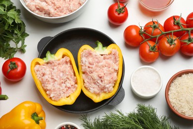 Raw stuffed peppers with ground meat and ingredients on white marble table, flat lay
