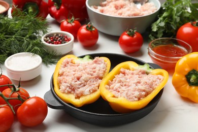 Photo of Raw stuffed peppers with ground meat and ingredients on white marble table