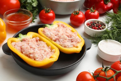 Photo of Raw stuffed peppers with ground meat and ingredients on white marble table