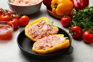 Photo of Raw stuffed peppers with ground meat and ingredients on light grey table
