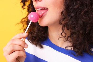 Photo of Woman with lollipop on yellow background, closeup