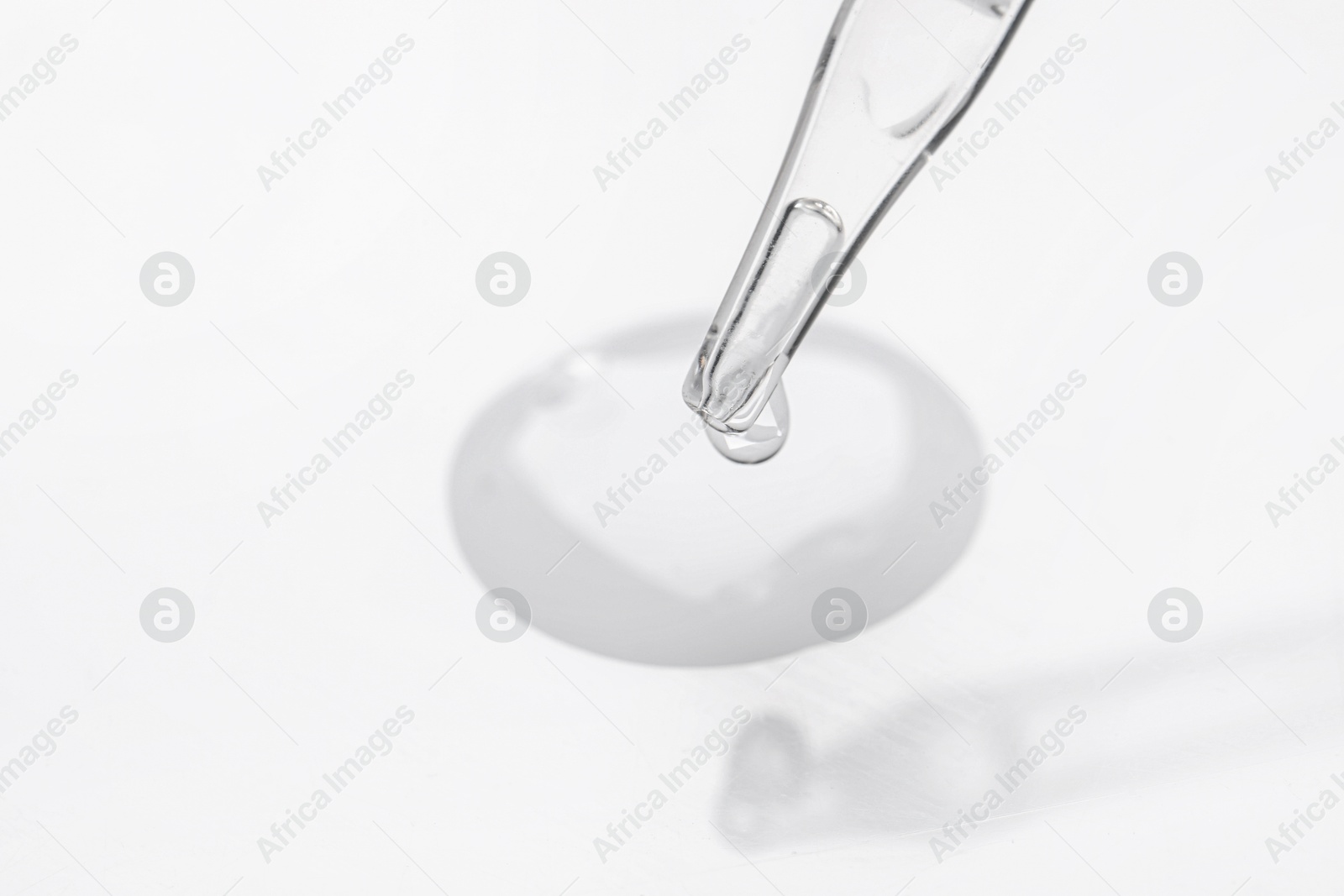 Photo of Glass pipette and transparent liquid on white background, closeup