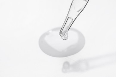 Glass pipette and transparent liquid on white background, closeup