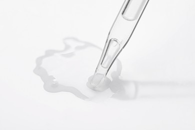 Glass pipette and transparent liquid on white background, closeup