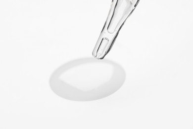 Photo of Glass pipette and transparent liquid on white background, closeup