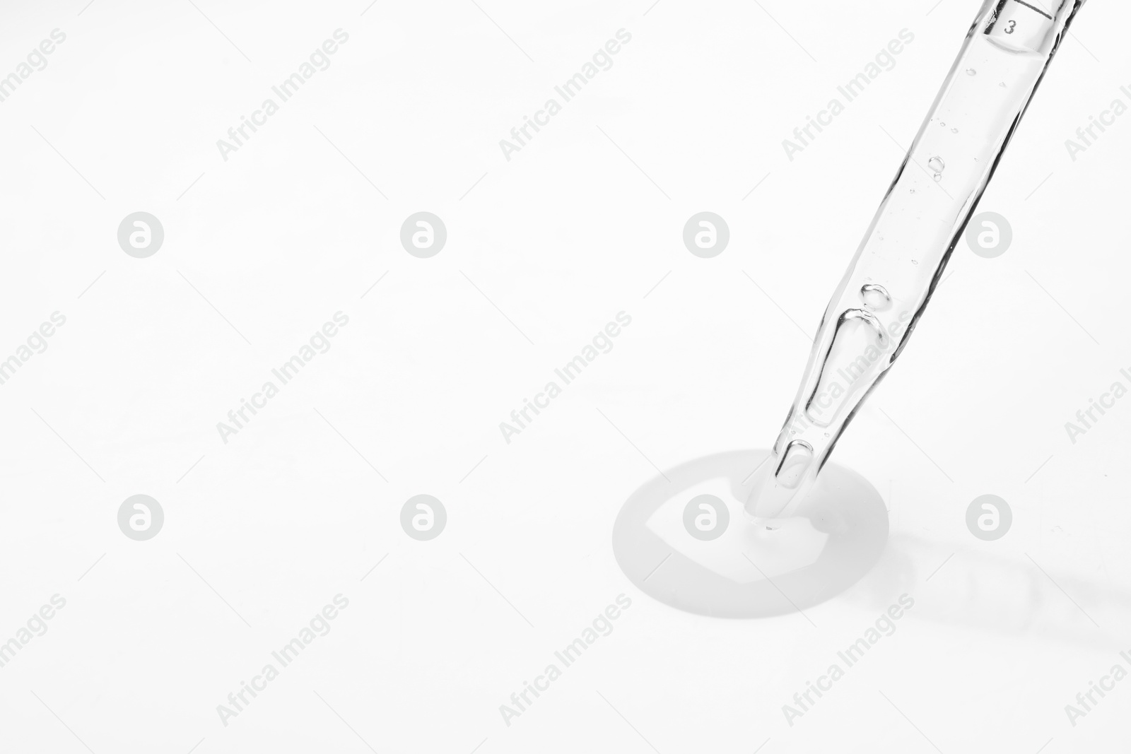 Photo of Glass pipette and transparent liquid on white background, closeup. Space for text