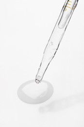 Glass pipette and transparent liquid on white background, closeup