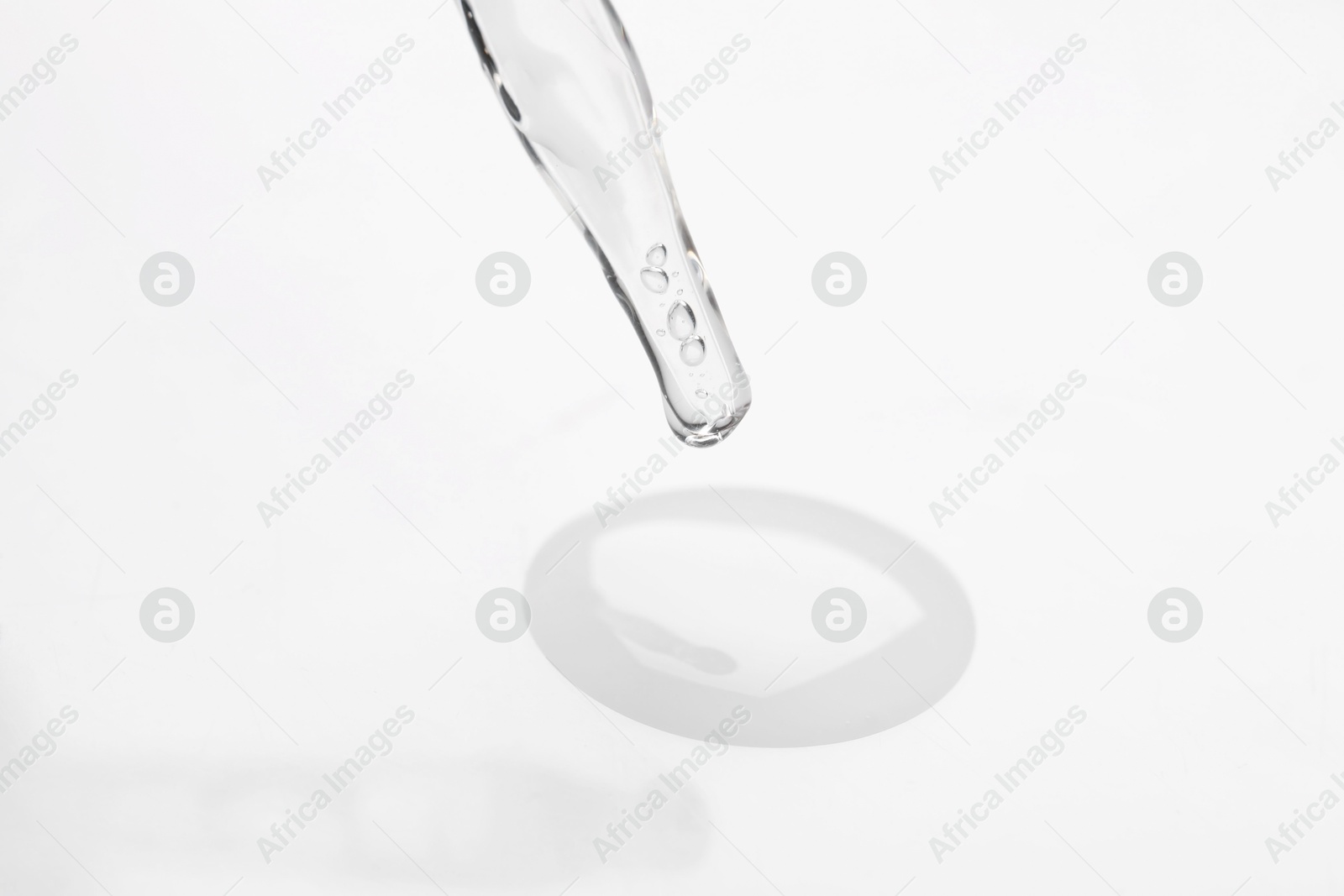 Photo of Glass pipette and transparent liquid on white background, closeup