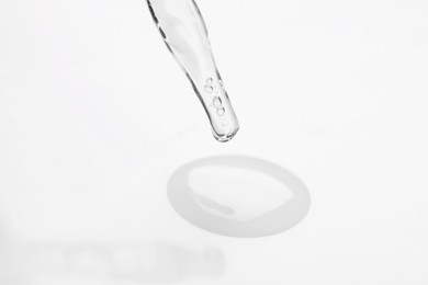 Glass pipette and transparent liquid on white background, closeup