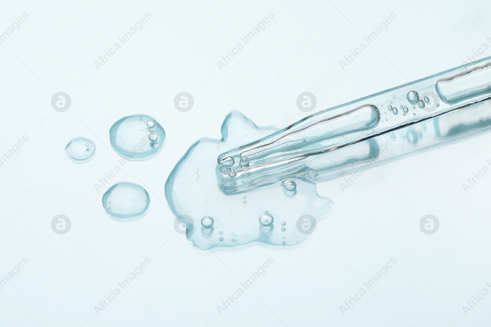 Photo of Glass pipette and transparent liquid on light background, closeup