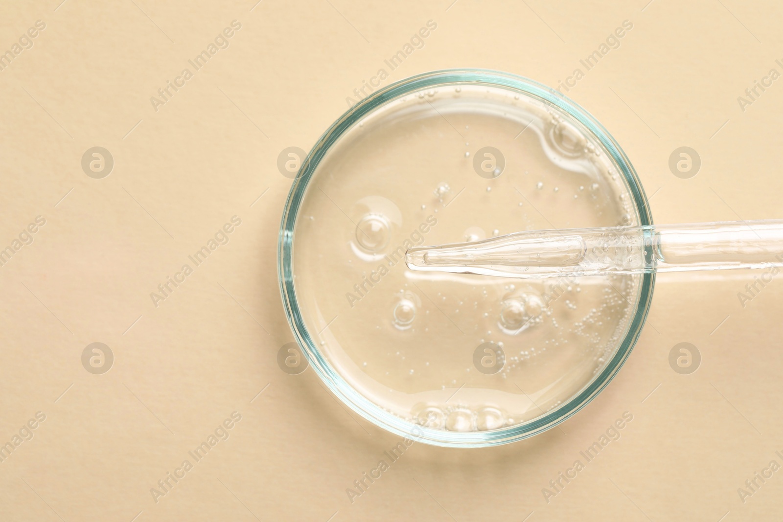Photo of Glass pipette and petri dish with liquid on beige background, top view