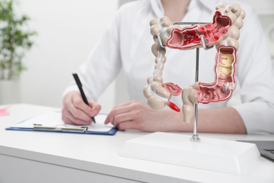 Photo of Doctor working at white table, focus on model of large intestine