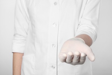 Photo of Doctor holding something on light grey background, closeup