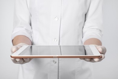 Photo of Doctor with tablet on light grey background, closeup