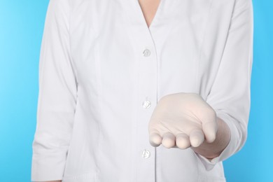 Photo of Doctor holding something on light blue background, closeup