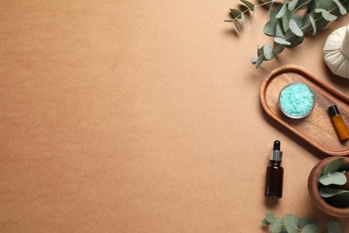 Different aromatherapy products and eucalyptus leaves on brown background, flat lay. Space for text