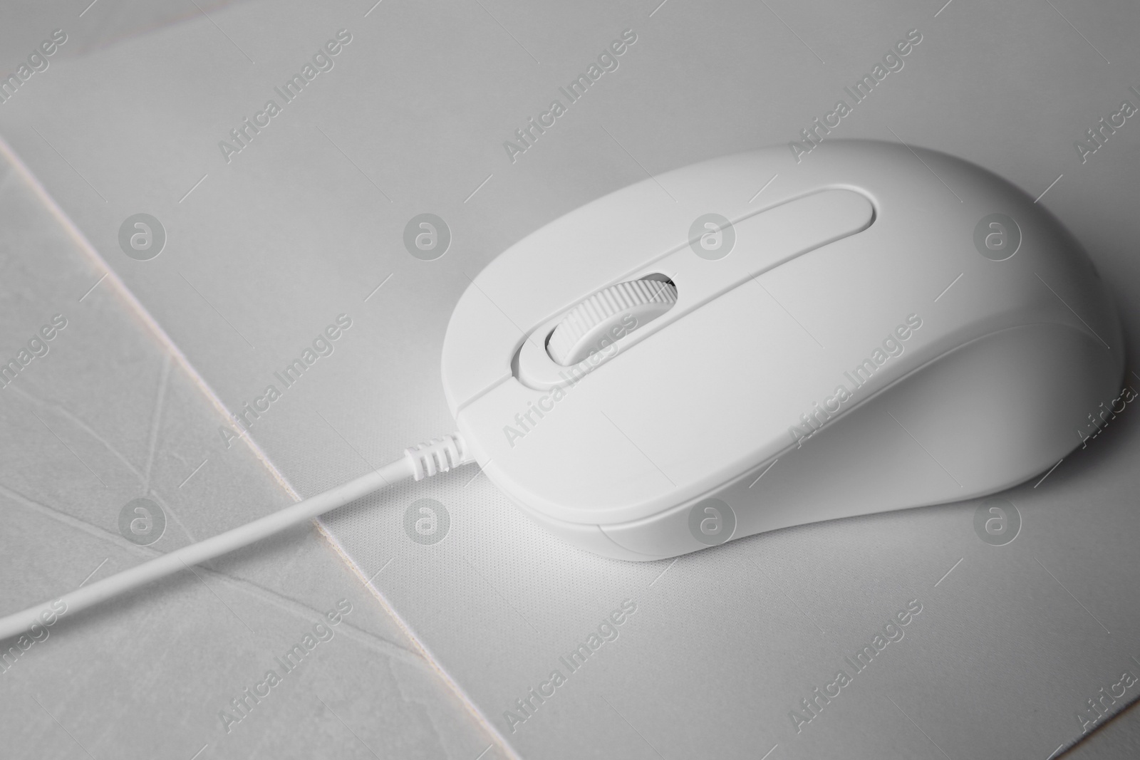 Photo of Wired mouse with mousepad on grey textured table, closeup