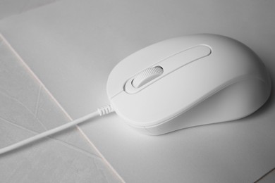 Photo of Wired mouse with mousepad on grey textured table, closeup