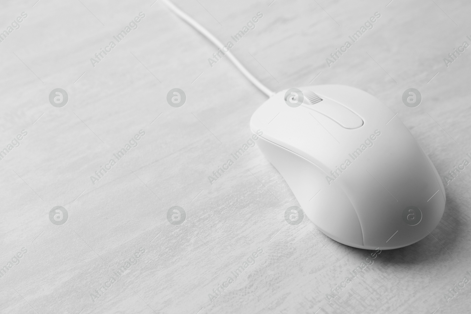 Photo of One wired mouse on grey wooden table, closeup. Space for text
